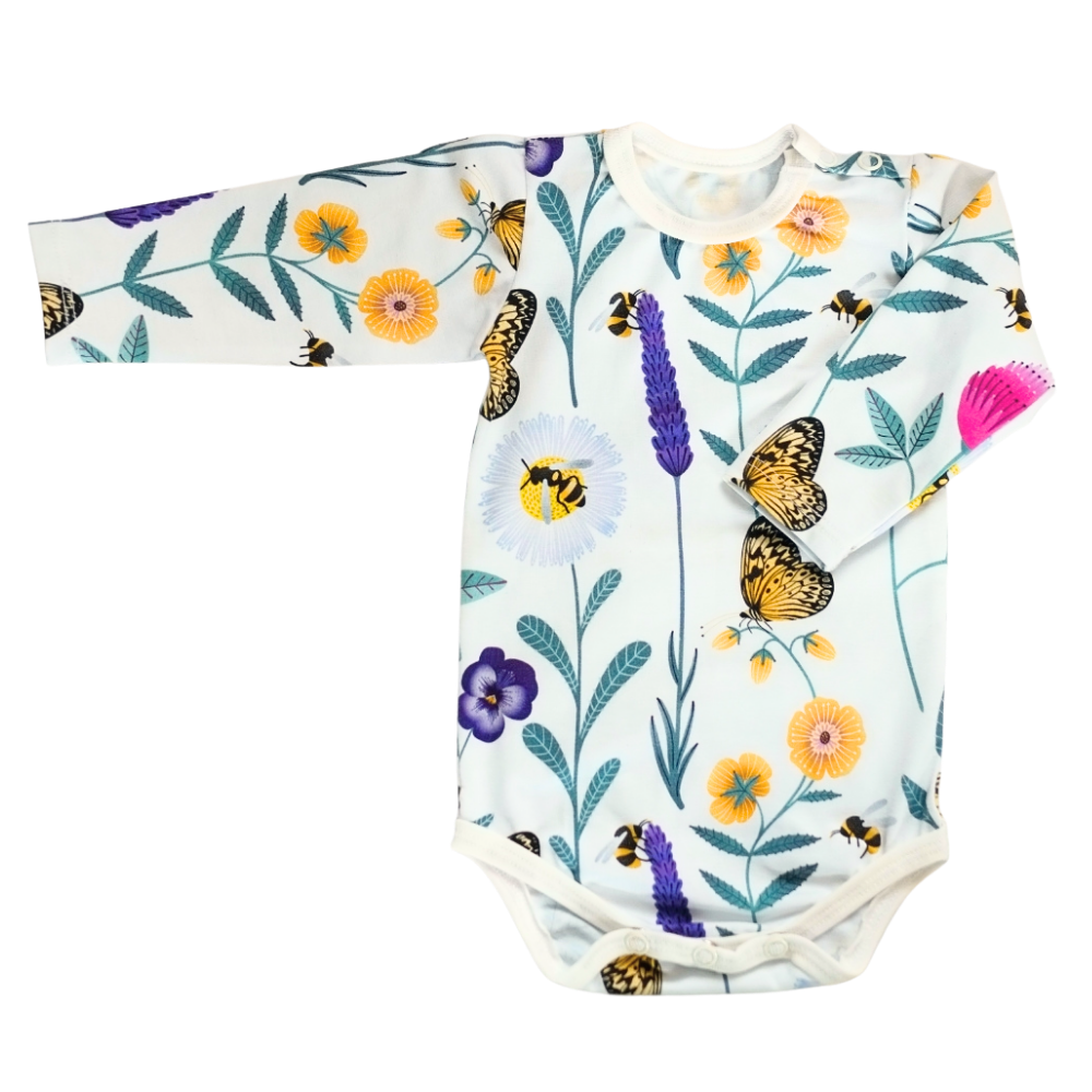 Baby body i vit ekologisk bomullsjersey med färgglatt mönster av blommor och insekter i lila, rosa, gult och turkos. Knäppning vid axel och gren.